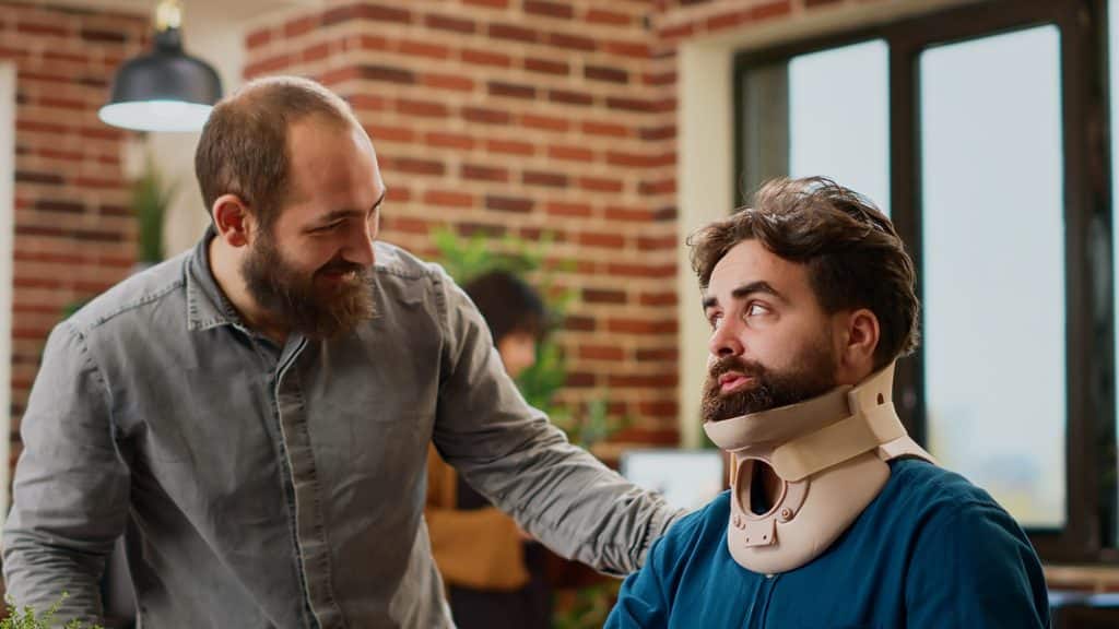 Office employee with neck collar brace working after accident injury